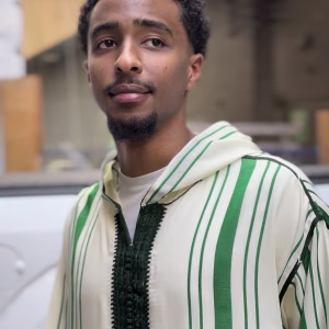 Man wearing green striped Moroccan djellaba standing in Calgary back alley, upper body view