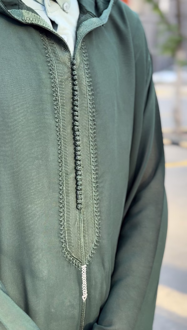 Close-up embroidery detail on dark green Moroccan thobe